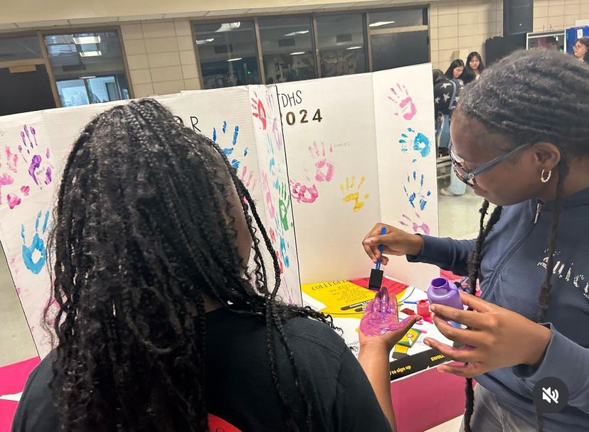 Seniors finger painting at the college bound station at the club fair. 