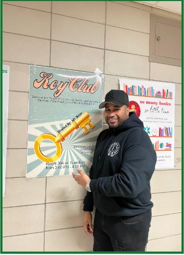 Key Club advisor Mr. Brito stands proudly in front of the poster advertising his club. 