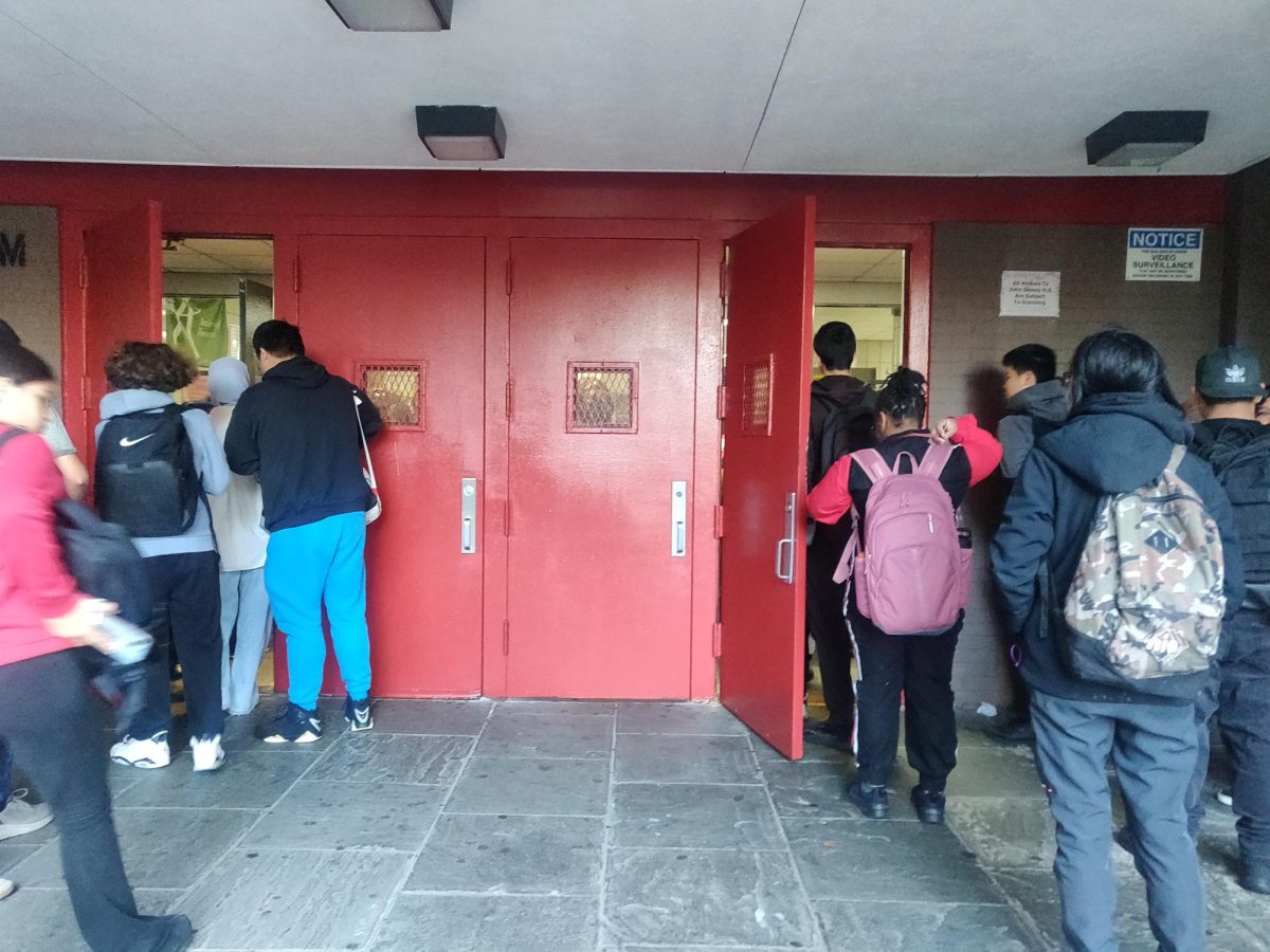 Students wait in line outside of school as scanning extends entry time. 