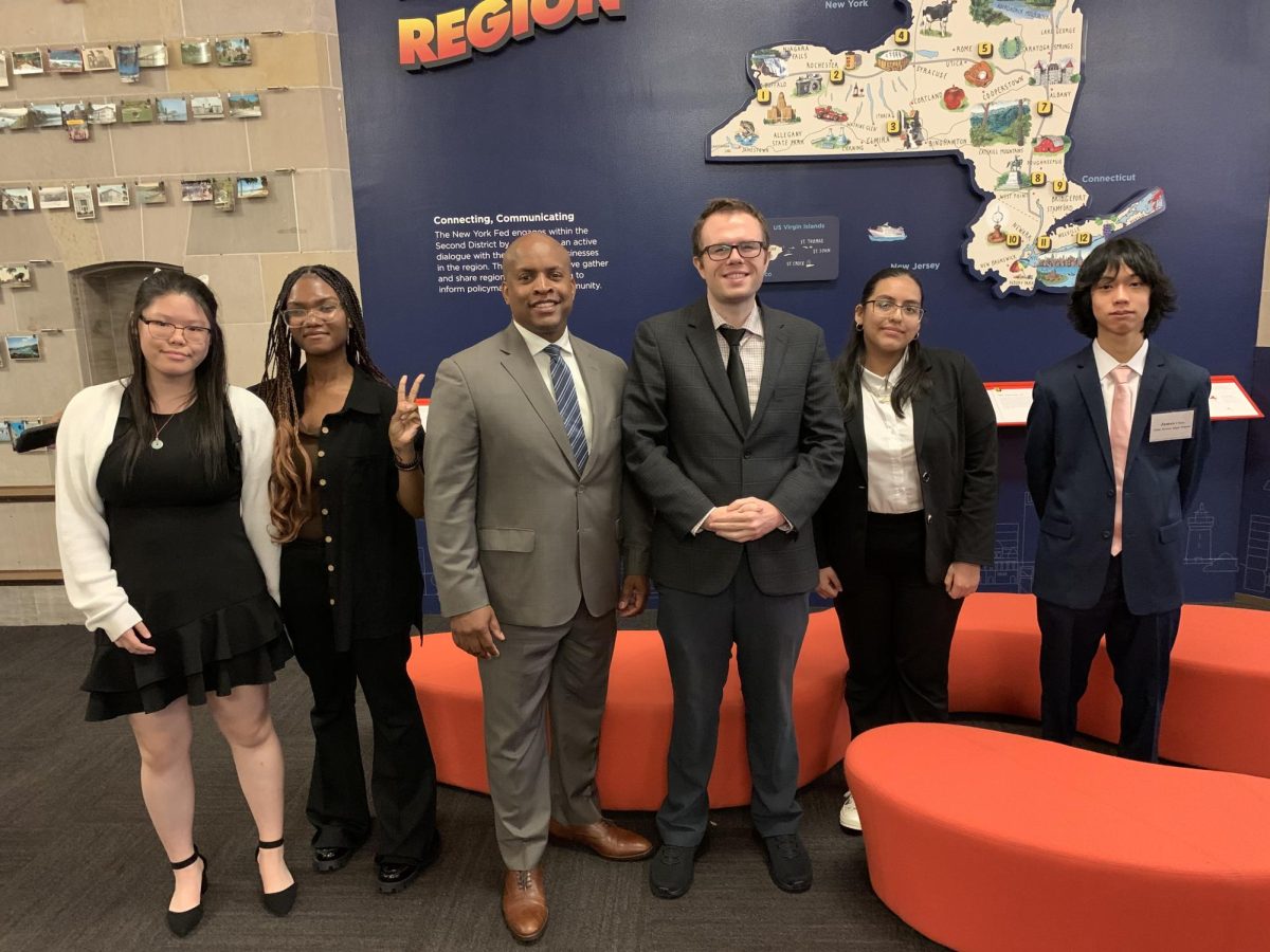 After presenting their solutions, Federal Reserve Interns pose at the entrance of the bank with Superintendent Michael Pryor and HE3AT Teacher Michael Luppino. 