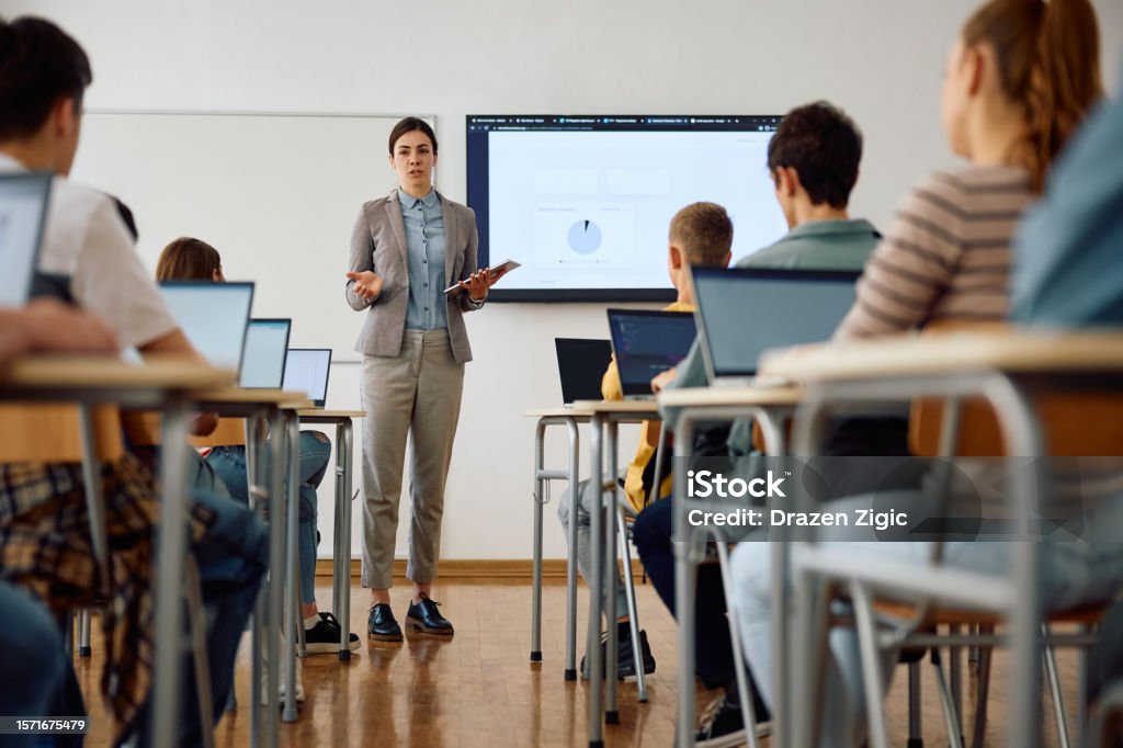 Computer science teacher giving a lecture to her high school students in the classroom.