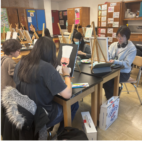 Students sitting together while painting their holiday canvases.