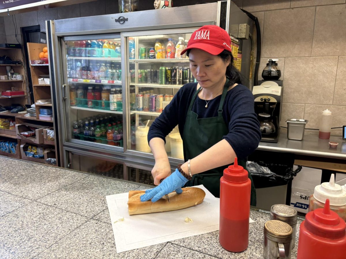 John's Deli cook Ming cutting a hero sandwich