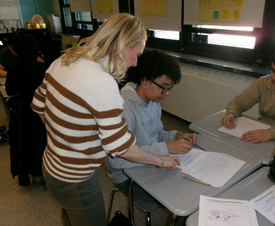 Chemistry Teacher Ms. Abbatemarco assisting a student in her class.